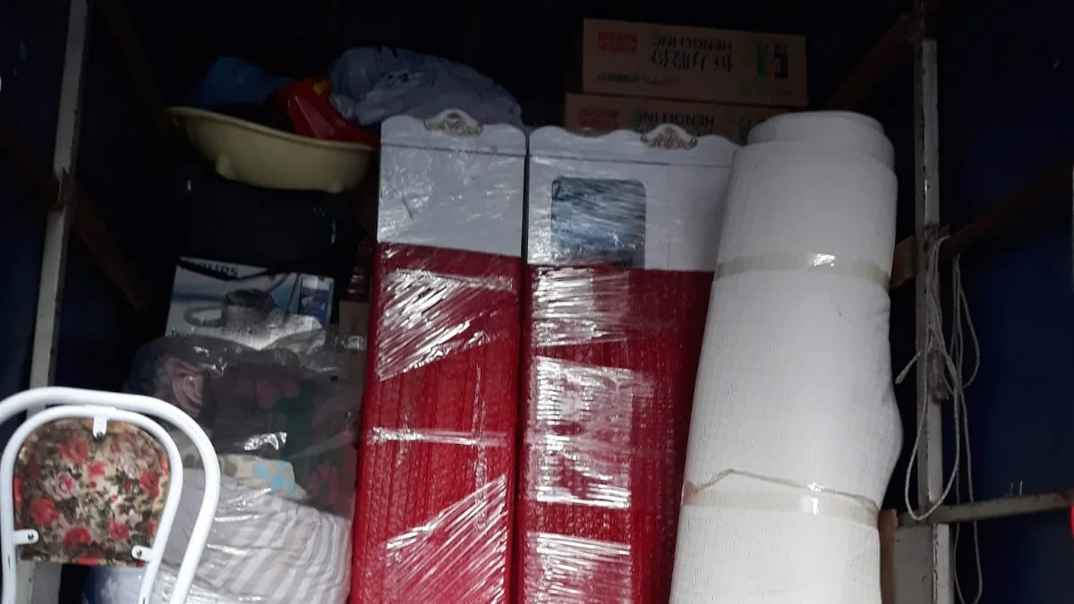 Kamyon kasasında balonlu naylonla sarılmış iki dolap ve rulo hâlinde halı