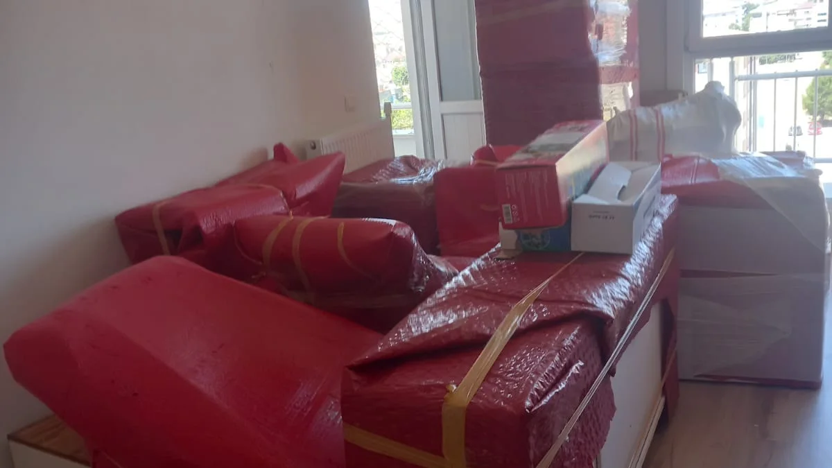 Odada balonlu naylon ve streçle sarılmış koltuk, dolap ve koliler